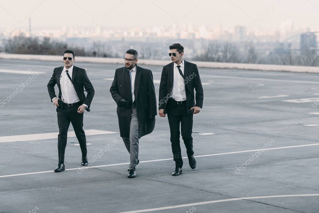 businessman and two bodyguards walking on helipad