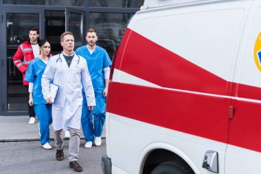 team of paramedics with doctor going from hospital to ambulance  clipart