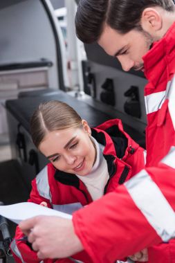 çekici erkek ve kadın sağlık görevlileri ambulans önünde belgeleri okuma