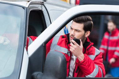 Ambulans duran ve tarafından taşınabilir radyo konuşmak genç yakışıklı erkek sağlık görevlisi