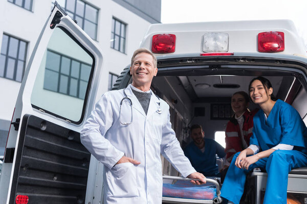 smiling paramedic team with working car