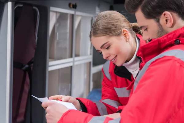 Leende Sjukvårdare Tittar Dokument Medan Stående Nära Ambulans — Stockfoto