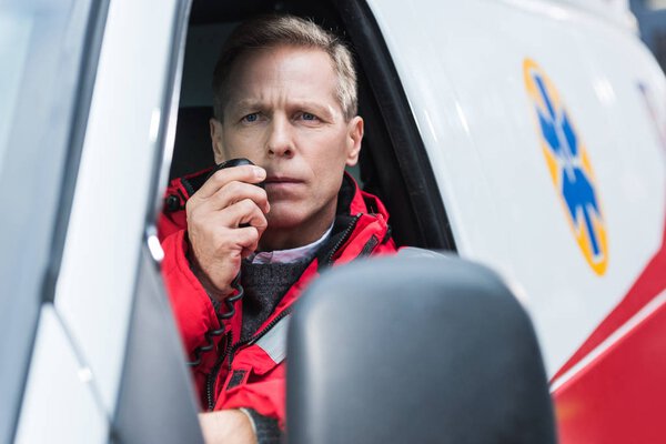 handsome middle aged paramedic talking by portable radio