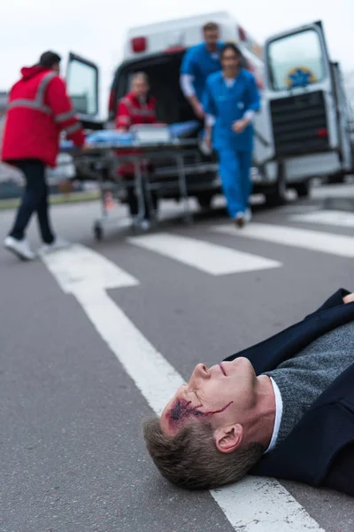 Ärzte Rennen Verletztem Mann Mittleren Alters Der Auf Der Straße — kostenloses Stockfoto