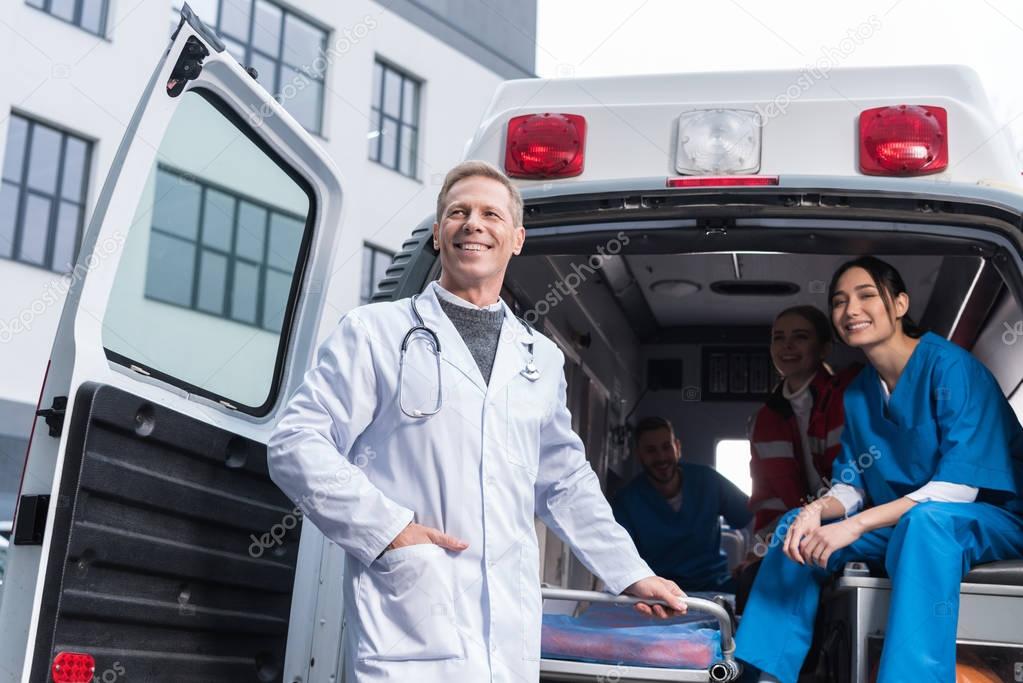 smiling paramedic team with working car