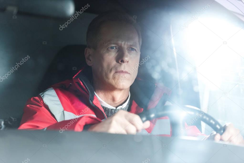 serious paramedic sitting in ambulance on driver seat 