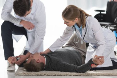 doctors checking pulse of unconscious man clipart
