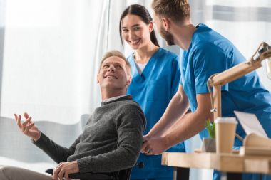 Doktor ve hasta hastanede konuşurken tekerlekli sandalye üzerinde gülümseyen