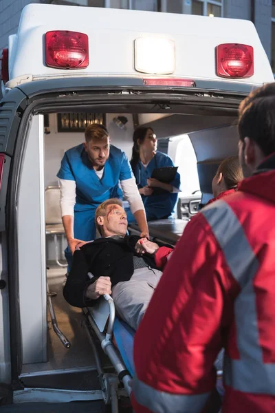 Παραϊατρικό Προσωπικό Που Κινείται Τραυματισμένο Άνθρωπο Ασθενοφόρο — Φωτογραφία Αρχείου