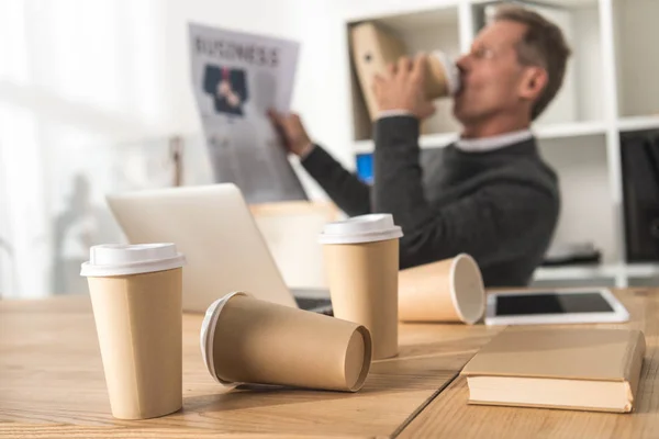 前景に散在の使い捨てのコーヒー カップでコーヒーを飲むビジネスマン — ストック写真