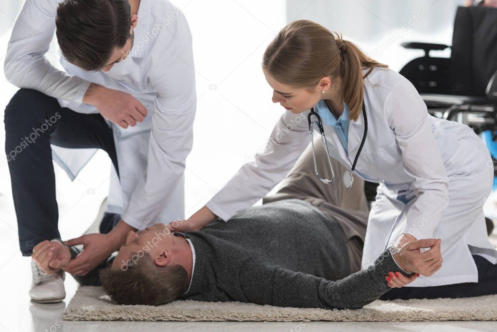 doctors checking pulse of unconscious man