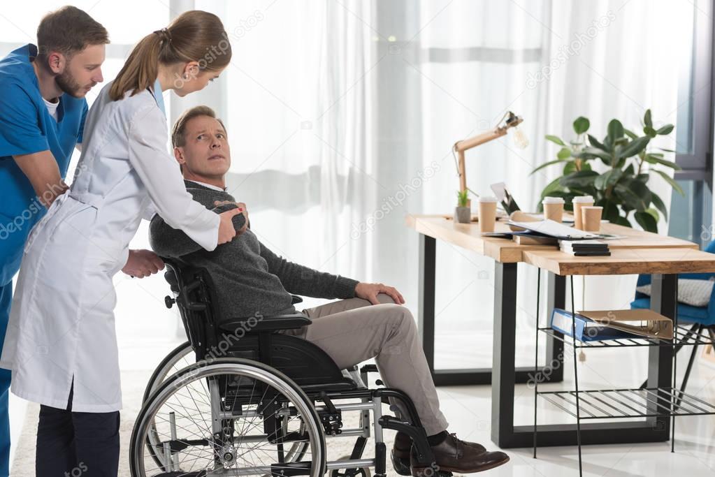 female doctor talking to mature man on wheelchair