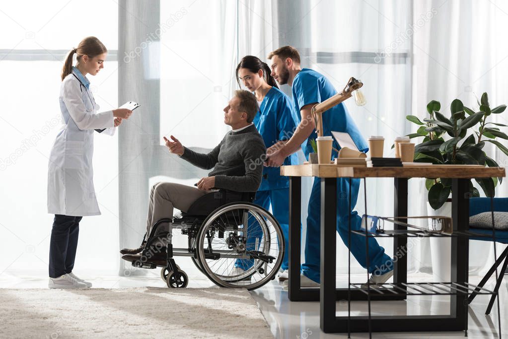 female doctor talking with middle aged patient on wheelchair 