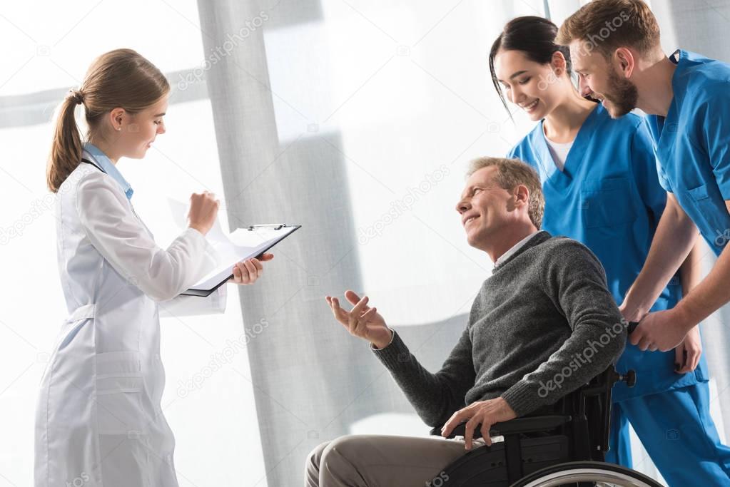 Doctor talking with middle aged patient on wheelchair 