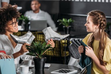 young female shoppers spending time in cafe clipart