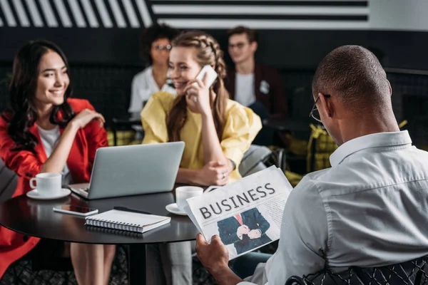 Afro Amerikaanse Man Leest Business Krant Terwijl Zijn Collega Praten — Gratis stockfoto