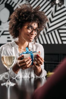 hediye tutarak ve kameraya bakarak genç Afro-Amerikan kadın