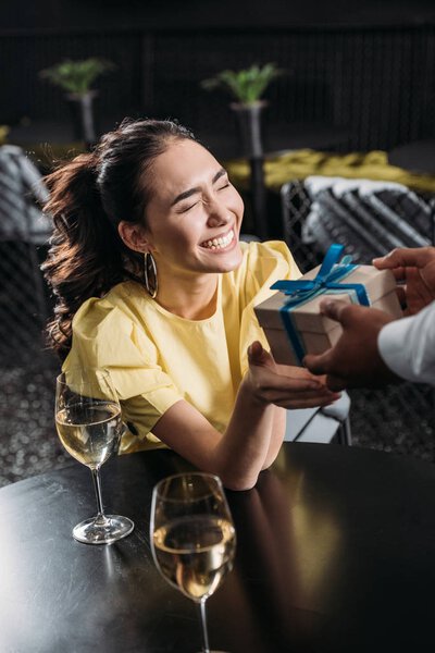 excited asian woman receiving anniversary gift from boyfriend
