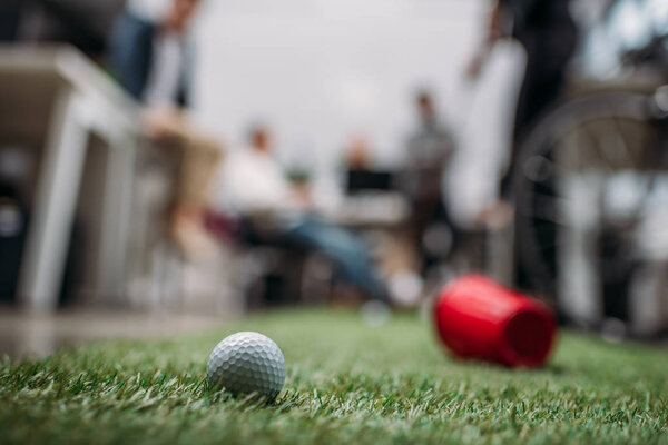 размытое изображение людей, играющих в мини-гольф в современном офисе
 