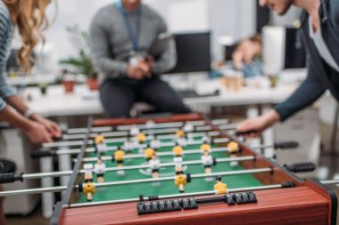 cropped image of people playing in table soccer at modern office clipart