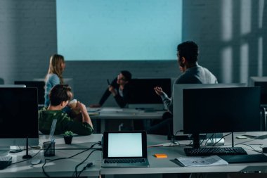 people watching presentation in office at nighttime. blank screen  clipart