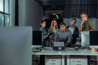 young people watching presentation in modern office at nighttime  clipart