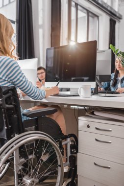 cropped image of woman in wheelchair using graphics tablet at modern office clipart