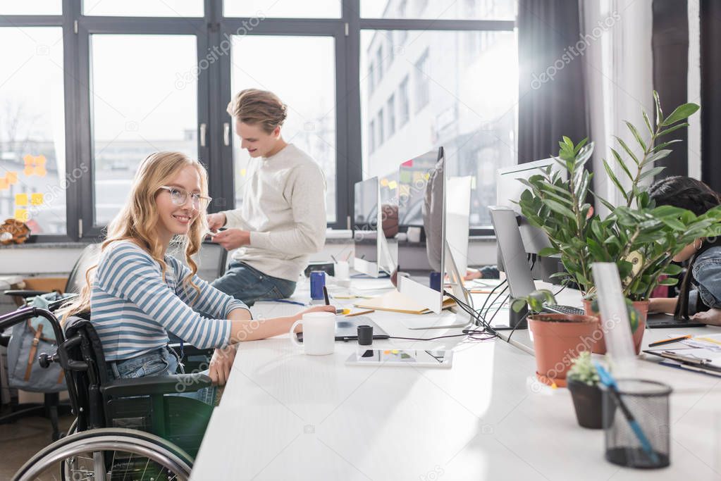 happy incapacitated person in wheelchair working at modern office