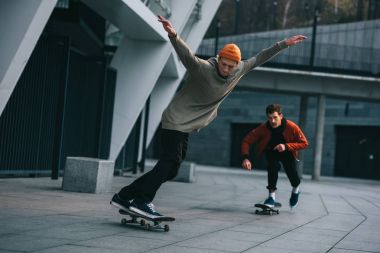 handsome young men riding skateboards in urban location clipart