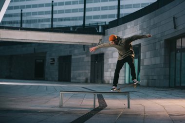 skateboarder balancing with board on bench in urban location clipart