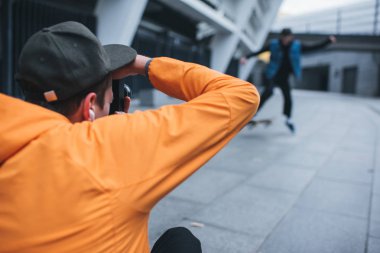 close-up shot of man taking photo of skateboarder doing trick clipart