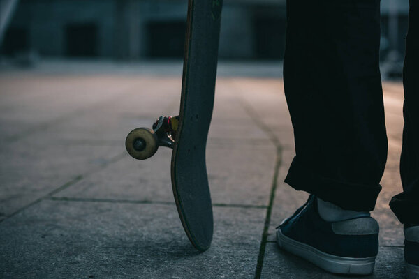 cropped shot of skateboarder standing with board