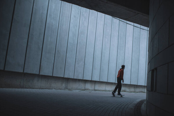 skateboarder riding at urban location with grey concrete walls