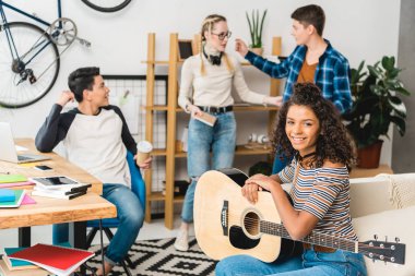 Afro-Amerikan holding gitar gülümseyen ve kameraya bakıyor