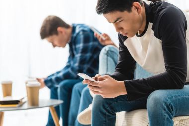 akıllı telefonlar ile oturan üç ciddi genç