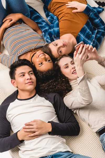 Overhead View Multiethnic Friends Lying Bed Looking Smartphone — Stock Photo, Image