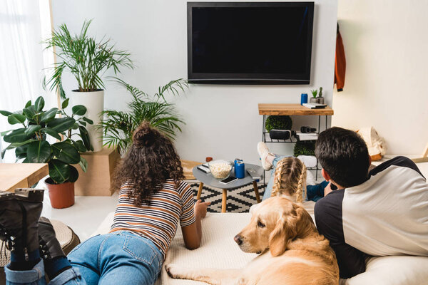 подростки смотрят телевизор и лежат в постели с собакой
