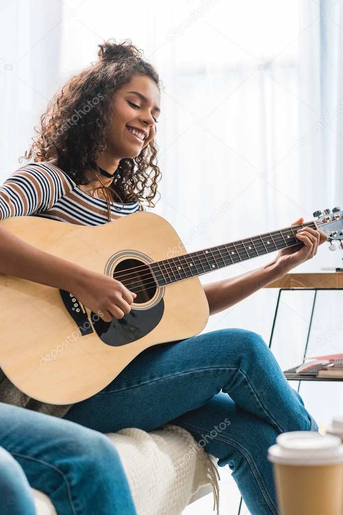 african american girl playing acoustic guitar