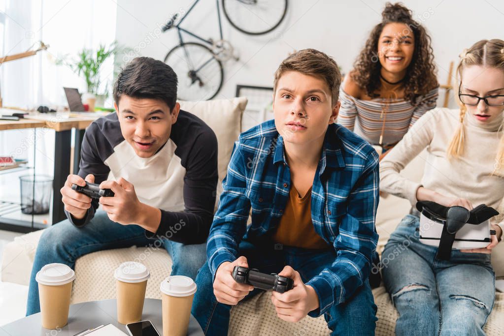 group of multiethnic teens playing video game at home