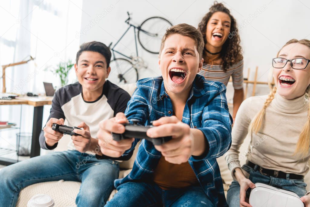 laughing multicultural teens playing video game
