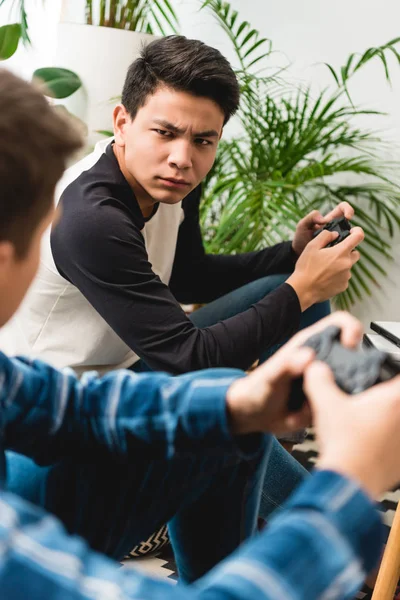 ビデオ ゲームをプレイしながらお互いを見て怒っている十代の少年たちのトリミングの画像 — ストック写真