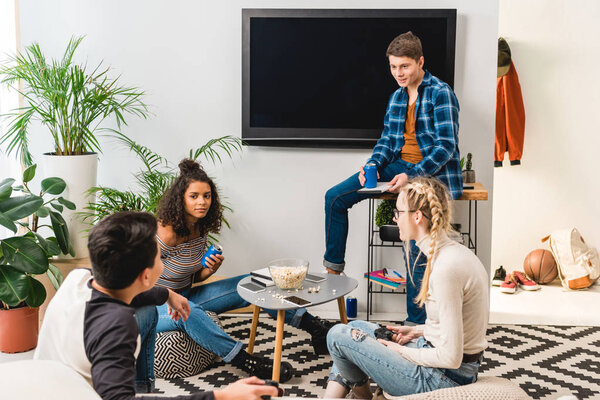 multicultural teens talking and drinking soda from cans