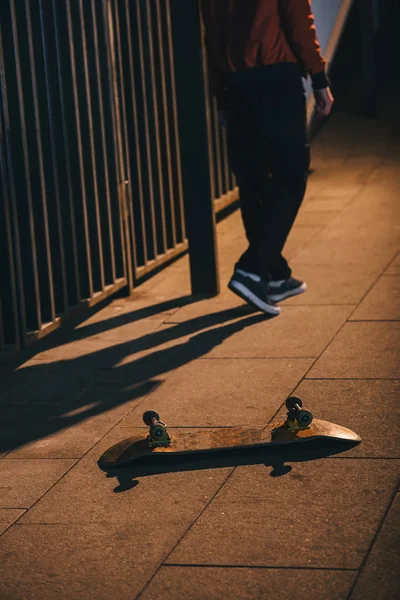 cropped shot of man walking away from skateboard laying on floor