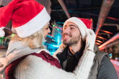 Noel Baba şapkaları birbirlerine pistinde gülümseyen mutlu genç Çift