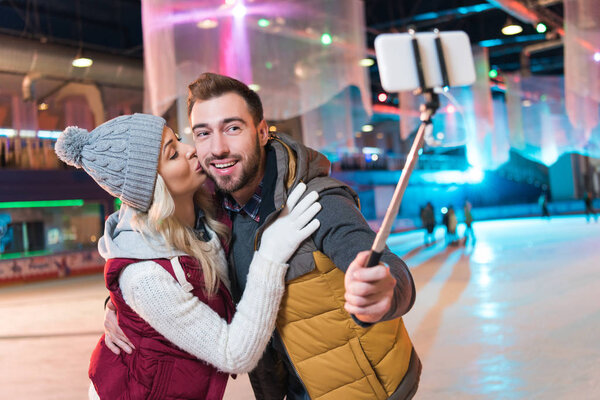 happy young couple taking selfie with smartphone on rink