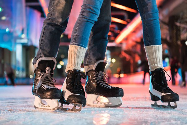 close-up partial view of young couple in skates ice skating on rink