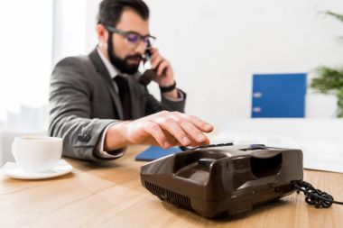 businessman dialing number with stationary telephone in office clipart