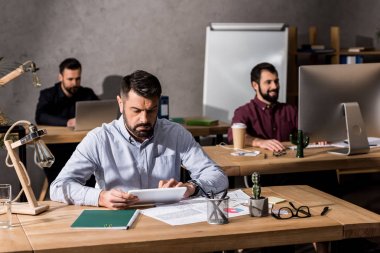 farklı dijital cihazlar ile çalışma masalarda oturan işadamları