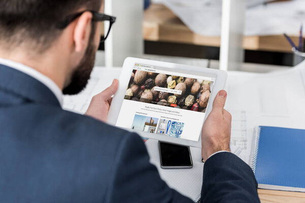 businessman holding tablet with loaded depositphotos page