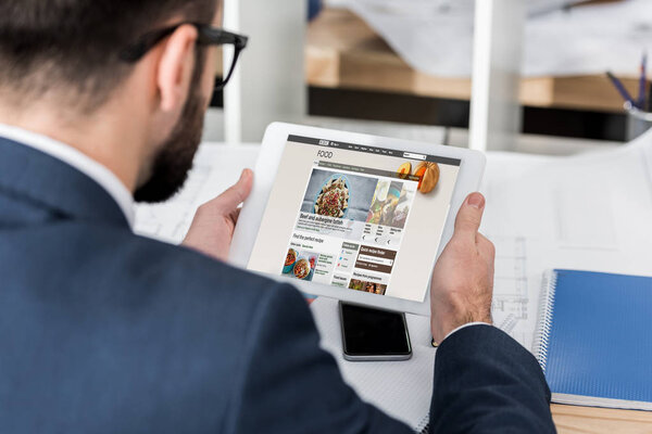businessman holding tablet with loaded bbc food page